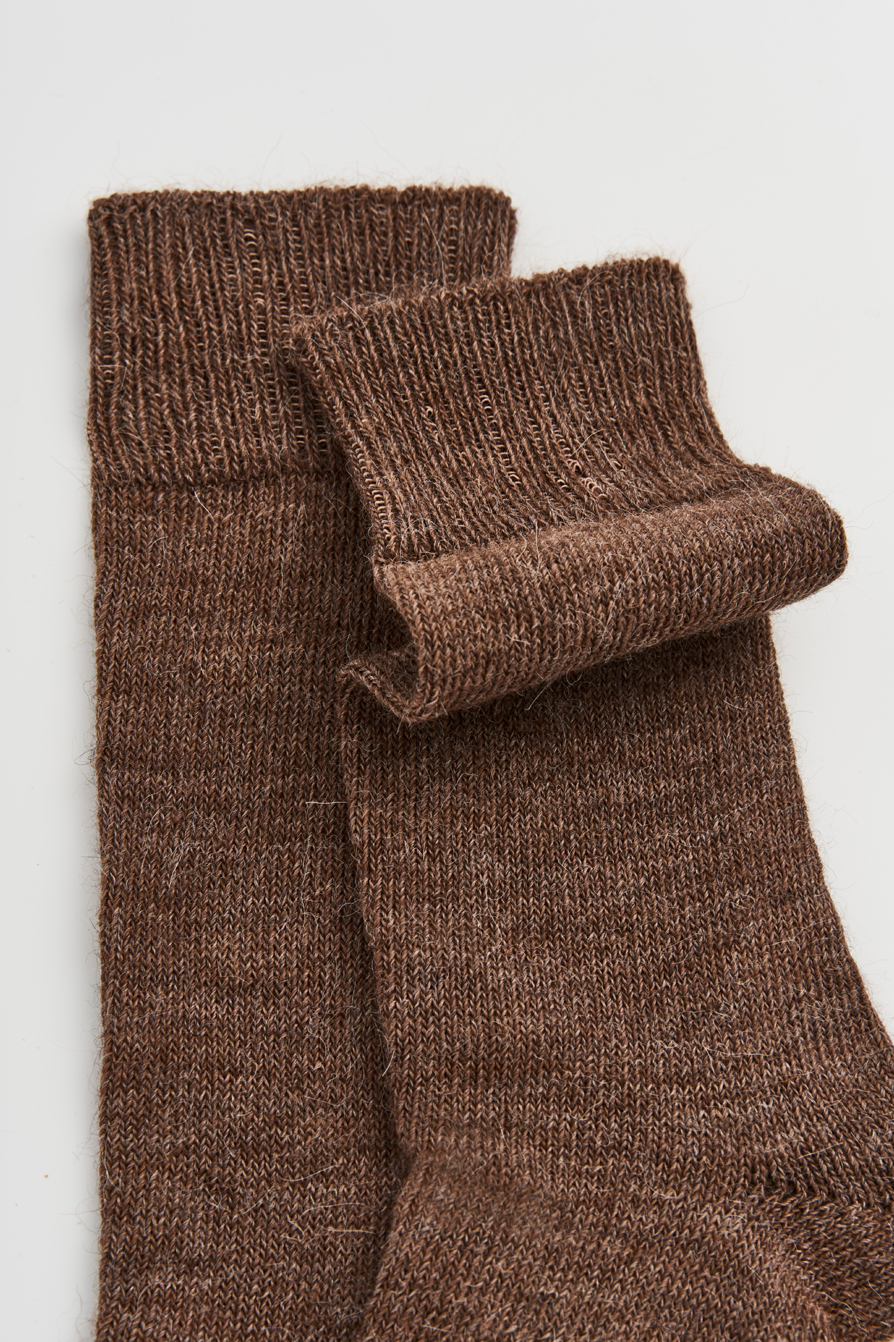 Women’s alpaca calf length socks in treacle brown with ribbed cuff and soft knit texture, close-up view for comfort when worn with leather boots.