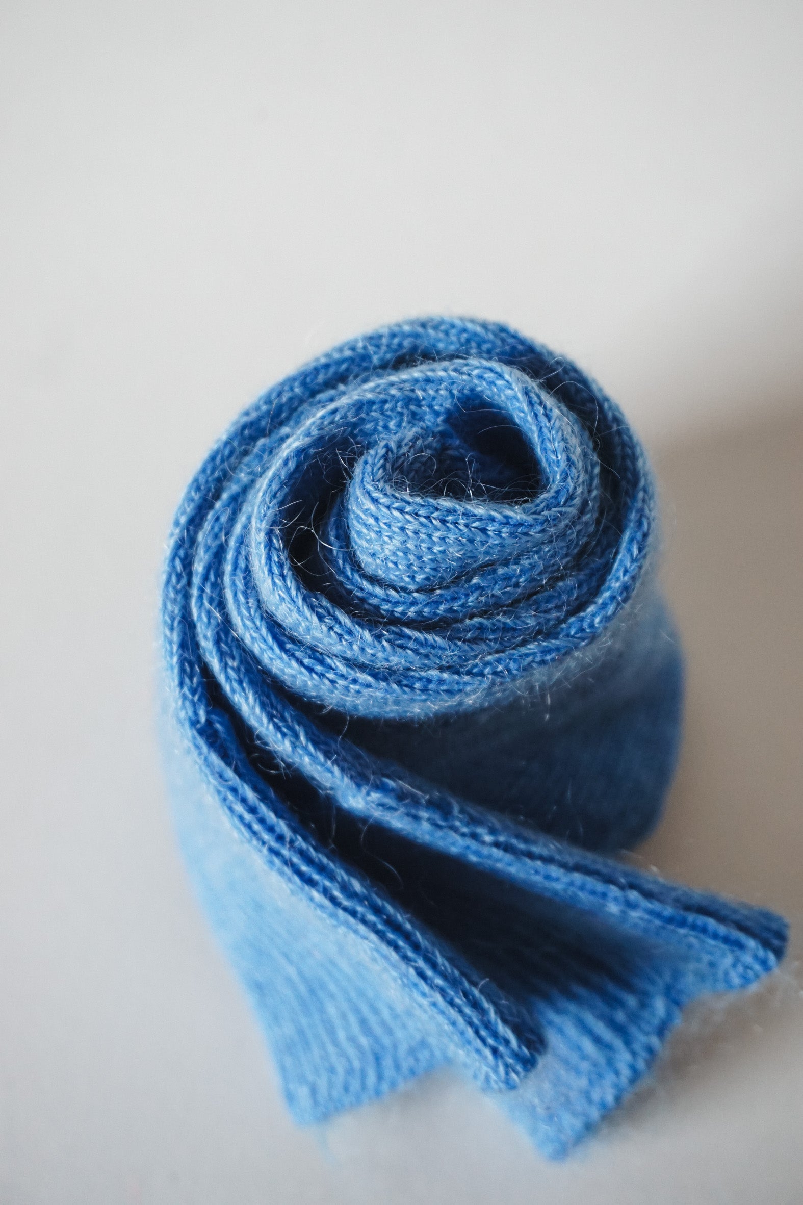 Women’s mohair calf length socks in cobalt blue with ribbed cuff and soft knit texture for comfort when worn with leather boots. Close up view of socks rolled up.