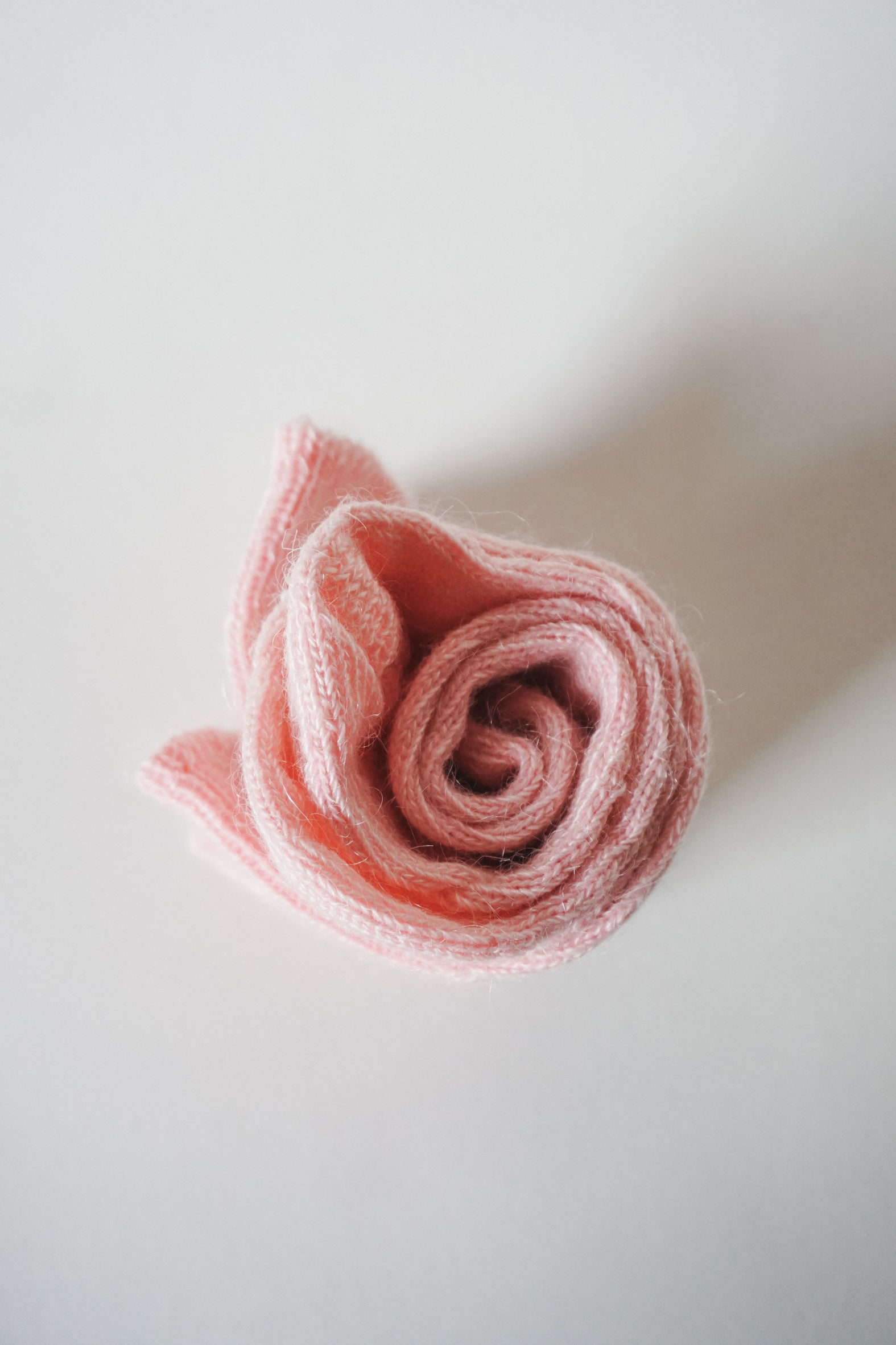 Women’s mohair calf length socks in light pink with ribbed cuff and soft knit texture for comfort when worn with leather boots. View of socks rolled up.