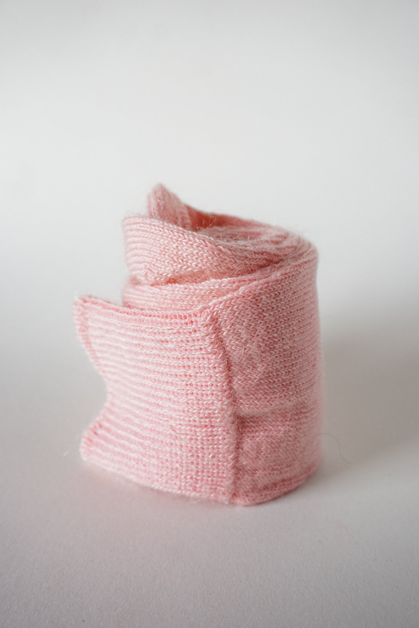 Women’s mohair calf length socks in light pink with ribbed cuff and soft knit texture for comfort when worn with leather boots. Close up view of socks rolled up.