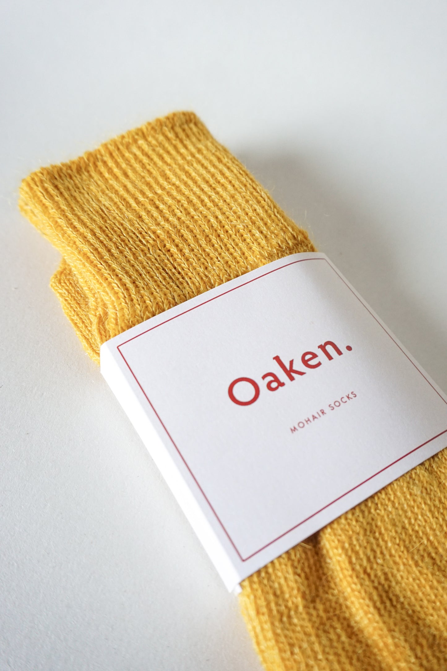 Women’s mohair calf length socks in yellow with Oaken packaging close up, ideal for wearing with smart casual leather boots.