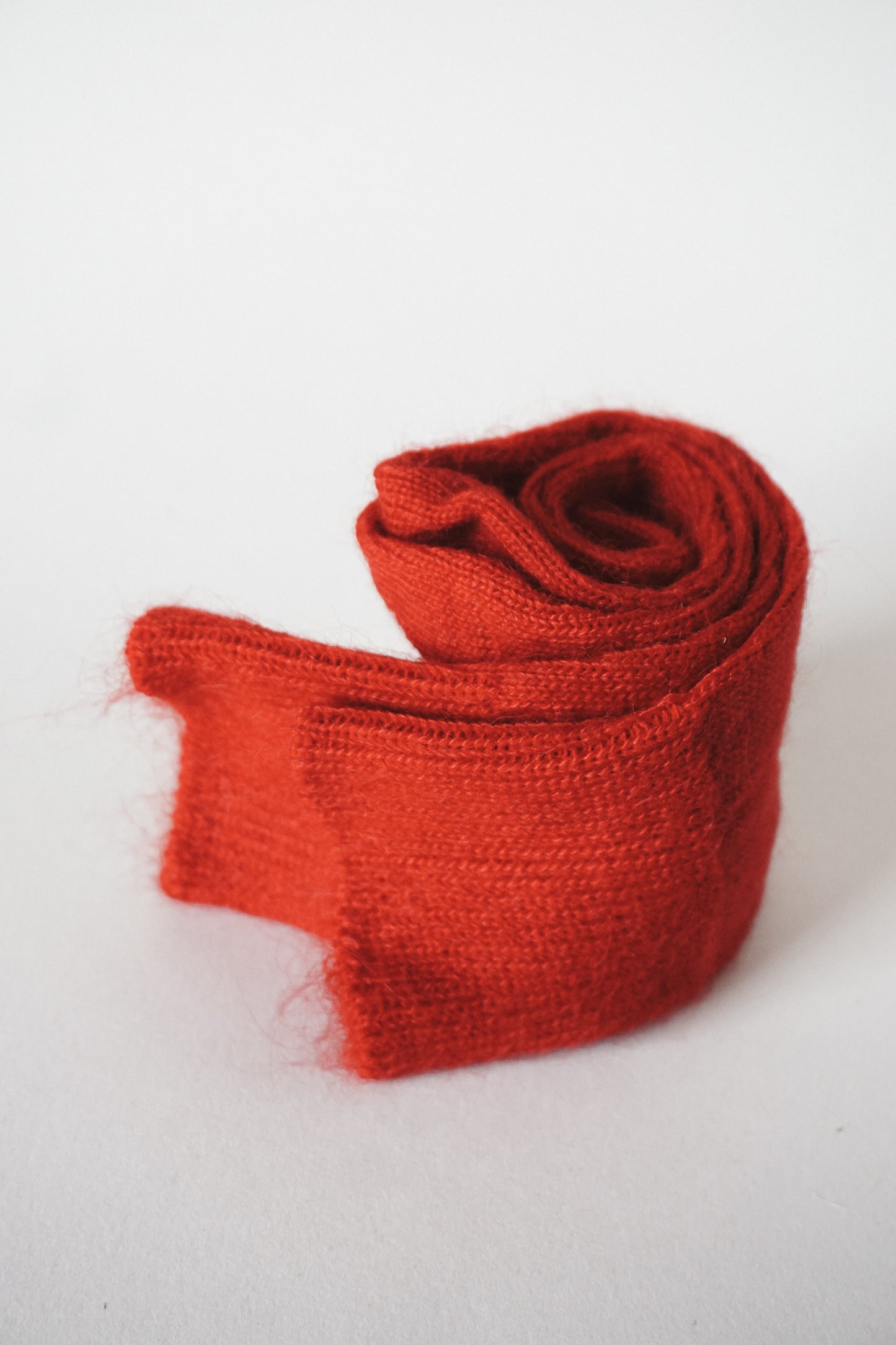 Women’s mohair calf length scarlet red socks with ribbed cuff and soft knit texture for comfort when worn with leather boots. View of socks rolled up.