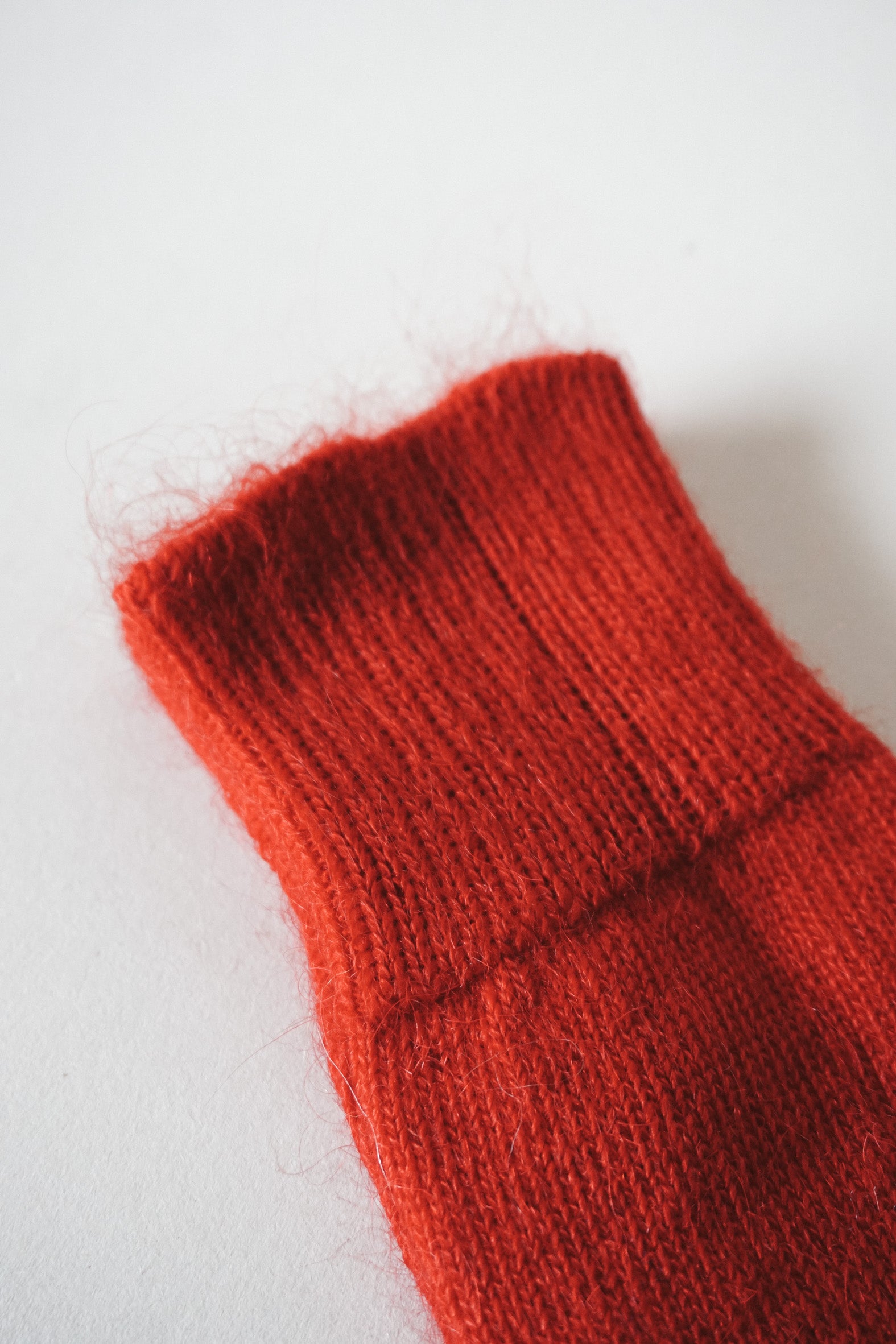 Women’s mohair calf length red socks with ribbed cuff and soft knit texture for comfort when worn with leather boots. Close up view of socks.