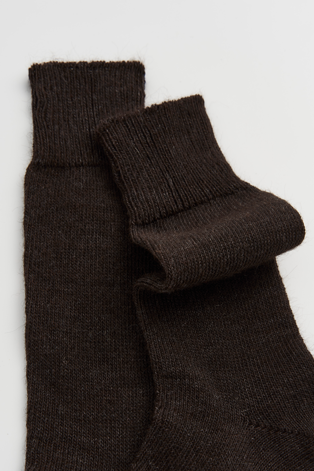 Women’s dark brown, alpaca calf length socks with ribbed cuff and soft knit texture, close-up view for comfort when worn with leather boots.