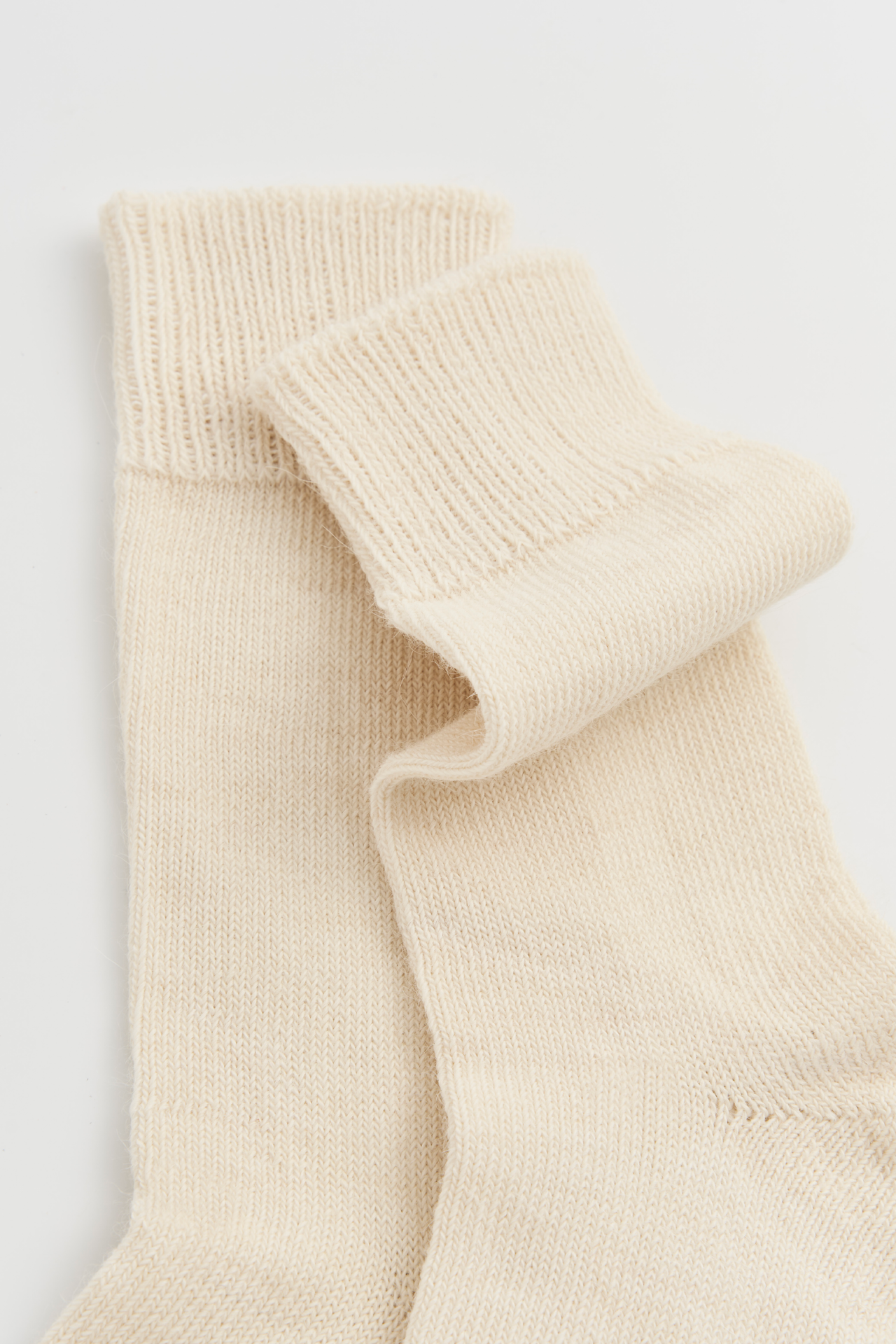 Women’s cream alpaca calf length socks with ribbed cuff and soft knit texture, close-up view for comfort when worn with leather boots.