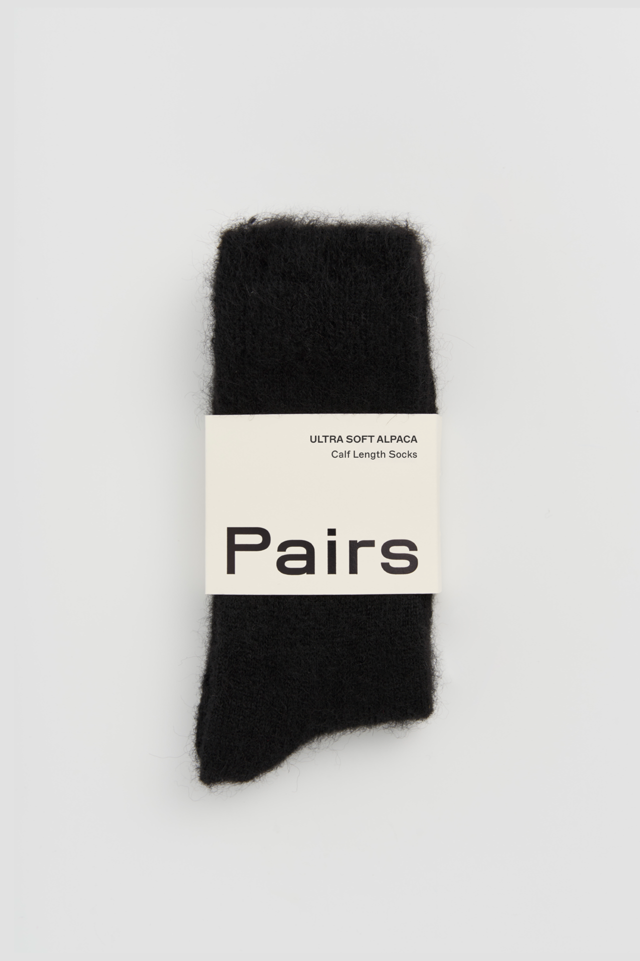 Women’s ultra soft alpaca calf length socks in black with Pairs packaging, ideal for wearing with smart casual leather boots.